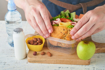Healthy food for school lunch concept. Care father making school lunch. Sandwich with healthy bread, meat, cheese, apple, cucumber, carrots, nuts, water, yogurt in container. Back to school concept.