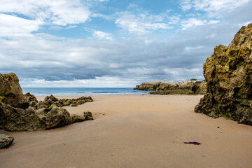 Fototapeta na wymiar Beautiful and quiet sandy beach with rocky outcrops in the Cantabrian Coast