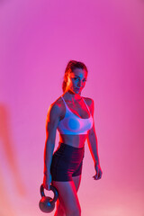 Fototapeta na wymiar Sportive woman training on a colorful background - Athletic fit adult female doing functional training fitness workout in a studio