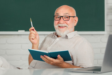 Smiling senior teachers teaching in the classroom on chalkboard. Teacher at university. Portrait of mature teacher professor at table in school. Senior teacher. Mature teacher. Professor on blackboard © Volodymyr
