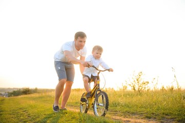 Father help his son ride a bicycle
