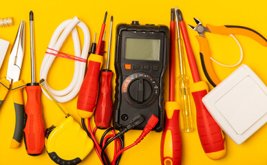 Electrician equipment on yellow background with copy space.Top view.Electrician tool set.Multimeter, tester,screwdrivers,cutters,duct tape,lamps,tape measure and wires.Flet lay. © Avocado_studio