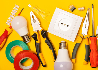 Electrician equipment on yellow background with copy space.Top view.Electrician tool set.Multimeter, tester,screwdrivers,cutters,duct tape,lamps,tape measure and wires.Flet lay. © Avocado_studio