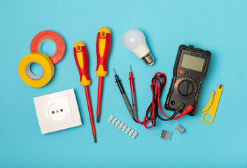 Electrician equipment on blue background with copy space.Top view.Electrician tool set.Multimeter, tester,screwdrivers,cutters,duct tape,lamps,tape measure and wires.Flet lay. © Avocado_studio