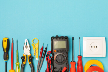Electrician equipment on blue background with copy space.Top view.Electrician tool set.Multimeter, tester,screwdrivers,cutters,duct tape,lamps,tape measure and wires.Flet lay. © Avocado_studio