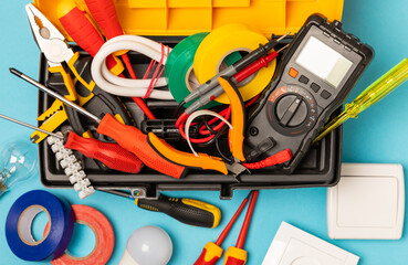 Electrician equipment on blue background with copy space.Top view.Electrician tool set.Multimeter, tester,screwdrivers,cutters,duct tape,lamps,tape measure and wires.Flet lay.