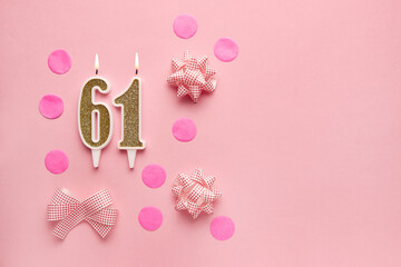 Number 61 on pastel pink background with festive decor. Happy birthday candles. The concept of...