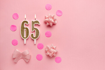 Number 65 on pastel pink background with festive decor. Happy birthday candles. The concept of celebrating a birthday, anniversary, important date, holiday. Copy space. banner
