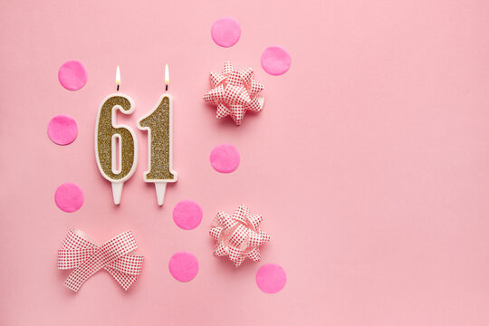 Number 61 on pastel pink background with festive decor. Happy birthday candles. The concept of celebrating a birthday, anniversary, important date, holiday. Copy space. banner