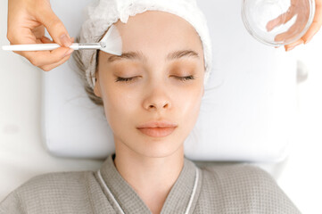 Facial skin care procedures in a beauty salon. The cosmetologist cleans the face of a beautiful...
