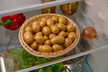 a basket of organic potatoes stands on a shelf in the refrigerator