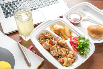 Meatball bento in the plastic box with the ultrabook on background. Busy lunch