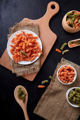 Raw gluten-free fusilli pasta from red lentils and chickpeas. Preparing for cooking. Organic food speciality on natural cutlery