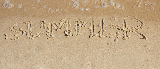 Inscription summer and sea wave on sand at beach. Vacation time