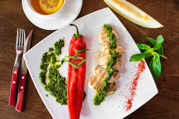 Grilled chiken fillet with vegetables in a black bowl over dark slate, stone or concrete background.Top view.
