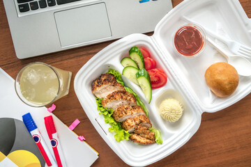 Meatball bento in the plastic box with the ultrabook on background. Busy lunch