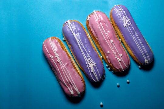 french dessert Eclair cake with pink  violet creme shining decoration Filling glaze with strawberries  blueberries Blue background  elegant natural fillings, pastel colors Place for text