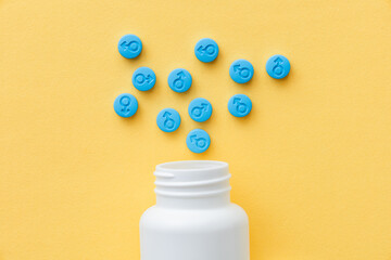 Pills for men. Male gender symbol on blue pills. Yellow background. Top view