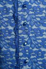 Detail of a blue women blouse made of guipure fabric with mother-of-pearl buttons, closeup