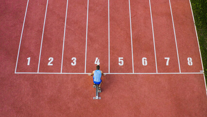 Caucasian male sprint runner alone on the athletic track, taking starting position and running in...
