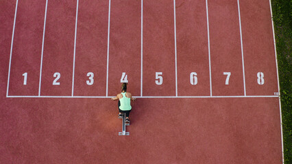 Caucasian female athlete alone on the athletic track, sprint running in line four, aerial directly...