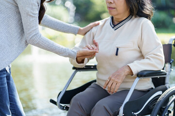 Obraz premium Nursing home. Young caregiver helping senior woman in wheelchair.