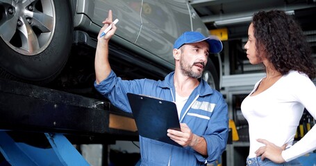 Automotive mechanic man in uniform explaining checklist car maintenance and repair to woman client...