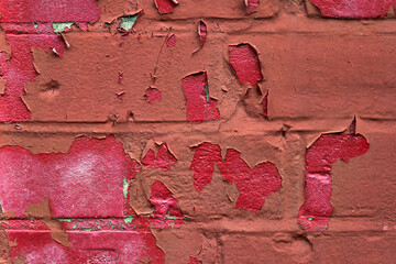 Red paint peeling off over brickwork to reveal pink paint underneath