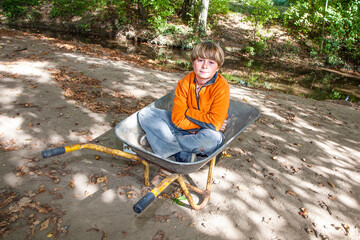 child sits in the wheel barrow and relaxes