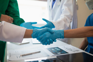 The medical team joins hands after the meeting and discusses the treatment of severely ill patients and can come to a conclusion on the surgical treatment of the patient. Medical team meeting concept