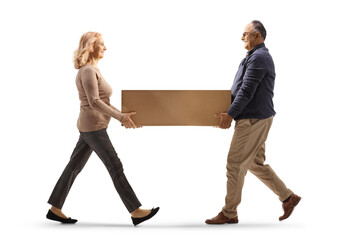 Full length profile shot of mature man and woman carrying a cardboard box together