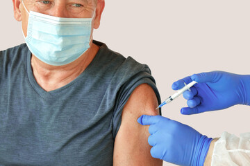 Fototapeta Doctor Vaccinating Senior Man In Clinic. Elderly People Vaccination. Giving COVID19, Flu, MPOX Coronavirus Vaccine Injection to Mature 60s Male. Face Mask. Protection of Older Patient. Gray Background obraz