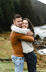 couple outdoors in the autumn season. lovers walk in a mountainous area near the river and forest. pastime of lovers during travel