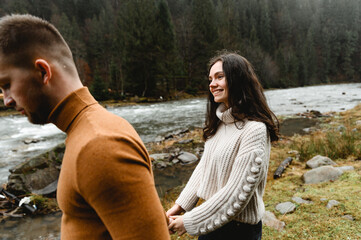 couple outdoors in the autumn season. lovers walk in a mountainous area near the river and forest....