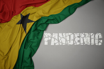 waving colorful national flag of ghana on a gray background with broken text pandemic. concept.