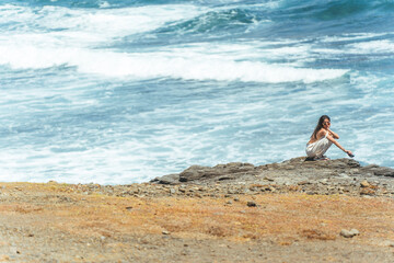 Fototapeta na wymiar Mulher sentada na praia observando o mar