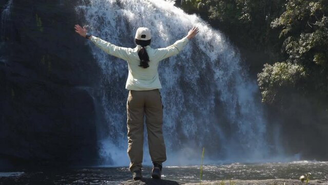Slow de turista erguendo os braços contemplando cachoeira do Bracuí no Brasil