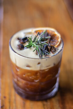 alcoholic drink decorated with rosemary, orange and roasted safflower beans. carajillo