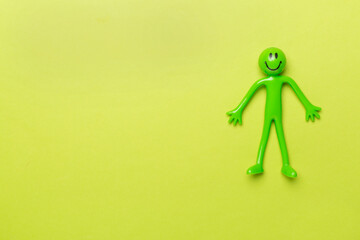 Human figure toy on color background, top view