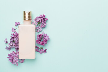 Composition with cosmetic bottle and flowers on color background, top view