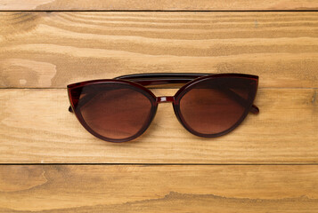 Sunglasses on wooden background, top view.