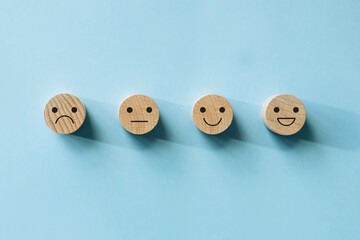Customer service evaluation and satisfaction survey concepts, evaluation, Increase rating. Happy face smile face icon on wood on blue background