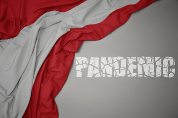 waving colorful national flag of austria on a gray background with broken text pandemic. concept.