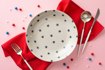 Fototapeta Celebrate USA in style with this eye-catching table serving concept. Top view plate, cutlery, napkin, and patriotic sprinkles on pastel pink backdrop. Customize space to convey your message or ad obraz