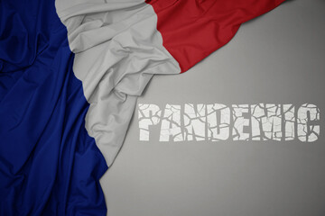 waving colorful national flag of france on a gray background with broken text pandemic. concept.