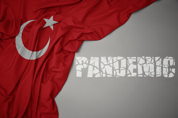 waving colorful national flag of turkey on a gray background with broken text pandemic. concept.