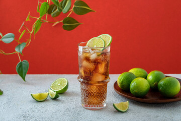 Fresh made Cuba Libre with rum, cola and lime on color background. Cold longdrink