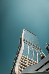 Skyscraper with turquoise glass windows under the sky at a sunny day