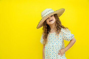 Summer concept. Happy child wear straw hat. cheerful little girl with curly hair on yellow...