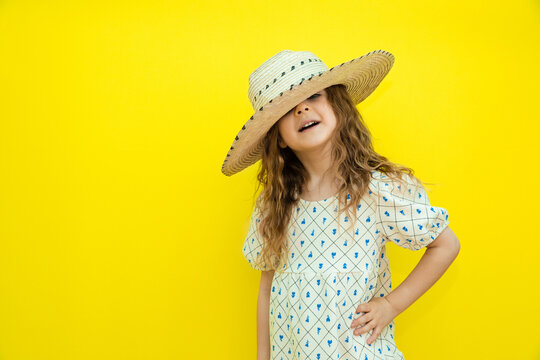 Summer concept. Happy child wear straw hat. cheerful little girl with curly hair on yellow background. Space for text. Mock up